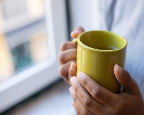 Person relaxing by a window with a warm drink