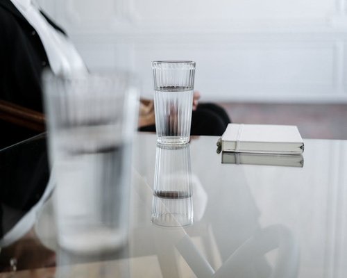A glass of water on a desk next to a notebook
